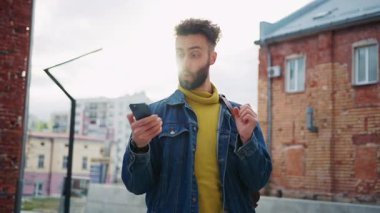 Çekici, mutlu, beyaz bir adamın portresi akıllı telefon ekranına bakarak heyecan verici haberler aldı. Neşeli öğrenci sohbetleri ve zaferi kutlama görüntüleri. Açık havada. Şehir sokağı