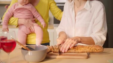 Mutlu lezbiyen çift yemek pişiriyor ve küçük kızına evde bakıyor.