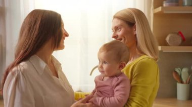 Birbirini seven mutlu lezbiyen çift içeride küçük bir kızla konuşuyor ve ilgileniyor.