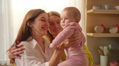 Neşeli, genç, homoseksüel bir ailenin kucağında küçük bir oğlan çocuğu.