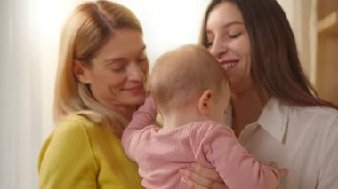 İki neşeli evli kadın hamileliğin tadını çıkarıyor ve bebeği öpüyor. Lgbt Ailesi