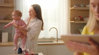 Sevgilisi tablet üzerinde çalışırken uzun saçlı mutlu kız bebekle oynuyor.