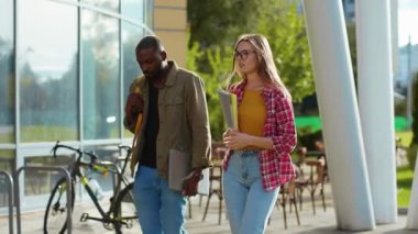 Kampüs binasının yakınında sınıflar hakkında iletişim kuran çeşitli, modern, çekici iki genç öğrenci. Melez insanlar. Eğitim ve dostluk.