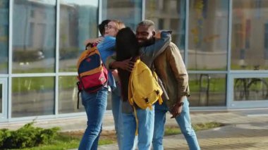 Modern üniversite öğrencileri sokakta öpüşüp kucaklaşıyorlar. Üniversitenin yakınlarında takılan çok ırklı, arkadaş canlısı genç insanlar..