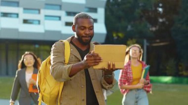 Dijital tablet kullanarak bitirdiği akademik projelerini çok ırklı arkadaşlarına gösteren mutlu Afro-Amerikanlar. Akıllı nesil. Başarı, duygular.