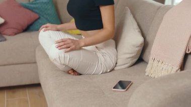 Kanepede oturup evde gözleri kapalı meditasyon yapan gergin genç bir kadın, telefon meditasyonu yarıda kesiyor. Kapatın. Yavaş çekim