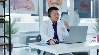Asyalı profesyonel erkek doktor sosyal mesafeler için dizüstü bilgisayarlı video kaset vasıtasıyla müşterilere danışmanlık yapıyor. Sağlık hizmetleri. Hastaneler. Uzak iletişim.