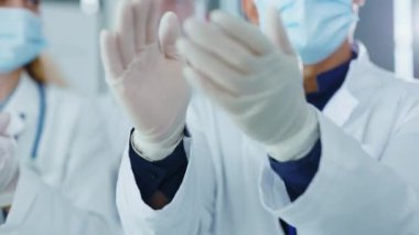 Tıp maskeli ve eldivenli çok yönlü doktorların modern hastanedeki iş görüşmesinde el çırpışları. Karantina tamamlandı. Yeni aşılar. Geliştirmeler.