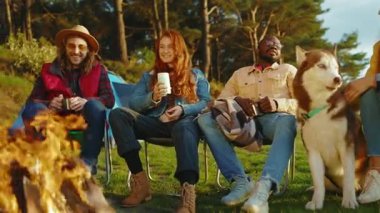 Doğada kamp ateşinin yanında oturan komik arkadaşlar. Gençler oyunlar hakkında konuşurlar, köpeklerin gülümsemesiyle mutlu olurlar. Tatil turizmi macerası. Yavaş çekim