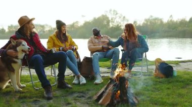 Doğada kamp ateşinin yanında oturan yakın arkadaşlar. Gençler oyunlar hakkında konuşurlar, köpeklerin gülümsemesiyle mutlu olurlar. Tatil turizmi macerası. Yavaş çekim
