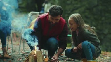 Baba ve kızı ormanda kamp ateşi çubukları kuruyor. Gülümsüyor. Aile zamanı. Orman mutluluğu doğa yangını. Kapatın. Yavaş çekim