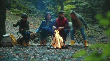 Portre ailesi sonbahar akşamı kamp ateşinin yanında oturur. Ebeveynleriyle birlikte çocuklar ormanda dinleniyorlar. Çocukluk ilişkisi kamp kuruyor. Kapatın. Yavaş çekim