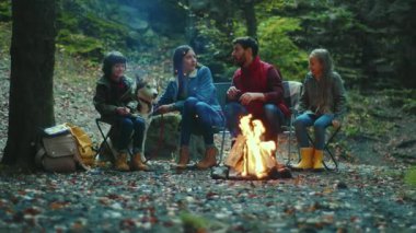 Aile, sonbahar akşamı kamp ateşinin yanında oturur ve korkunç hikayeler anlatır. Ebeveynleriyle birlikte çocuklar ormanda dinleniyorlar. Çocukluk ilişkisi kamp kuruyor. Kapatın. Yavaş çekim