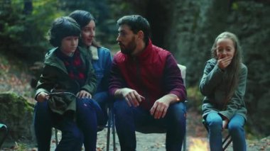 Orman ailesinde sonbahar akşamı kamp ateşinin yanında oturur ve korkunç hikayeler anlatırlar. Ebeveynleriyle birlikte çocuklar ormanda dinleniyorlar. Çocukluk ilişkisi kamp kuruyor. Kapatın. Yavaş çekim