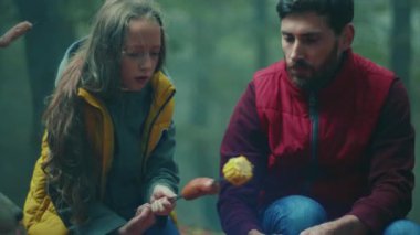 Yüz ailesi, sonbahar akşamı ormanda kamp ateşinin etrafında oturur. Ormandaki bir yangında sosis kızartmak. Dostluk mutluluğu şömineyi pişirir. Kapatın. Yavaş çekim