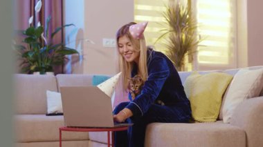 Sarışın, çekici bir kadın uzaktan doğum gününü arkadaşlarının video konferans laptopuyla kutlayan sevimli Bengal kedisini okşuyor. Tatillerde. Bağımsız yaşam tarzı. Evcil hayvanlar.