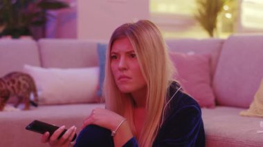 Üzgün sarışın kadın evde kalıp, mutsuz ifadeler sergileyen dramatik diziler izliyor. Duygusal bir film. Eğlence. Ev neonu.