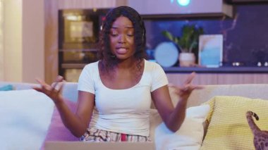 Kedi sohbeti yapan, gülümseyen Afro-Amerikan kadın dizüstü bilgisayar kullanıyor. Evde video var. Mesafe ilişkisi. Yavaş çekim