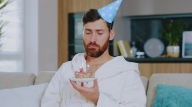 Mutsuz, üzgün, genç bir adam doğum gününü yalnız kutluyor. Pasta izleyip televizyon seyrediyor. Karantina sırasında oturma odasındaki kanepede oturmak. Evde kalıp Coronavirus 'u altüst etmek. Yavaş çekim