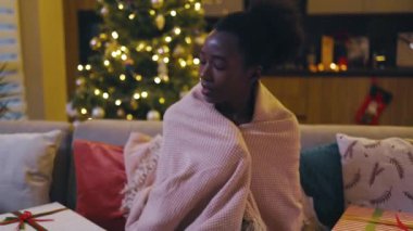 Ekoseye sarılmış, koltukta oturan korkmuş bir kadın. Korkuyu hisseder. Sokakta selamlar. Yeni yıl. Mutlu Noeller. Düşük hareket.