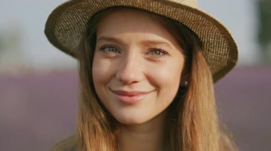 Bulanık çiçek tarlasında güzel, beyaz, genç, neşeli bir kadının portresi. Çekici mutlu kadın kameraya gülümsüyor. İnsanlar, yüzler ve ifade.