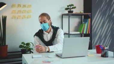 Genç iş adamı laptopta tıbbi koruma maskesiyle çalışıyor bilgisayar pandemik koronavirüs hastalığı işi covid-19 tıbbi korumalı iş yeri yavaş çekim