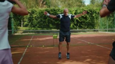 Oyuncular tenis maçından önce antrenörle atlamaya hazırlanıyorlar. Antrenman antrenmanı, spor salonu, spor salonu, erkek sporcu, spor salonu, yavaş çekim kapanıyor.