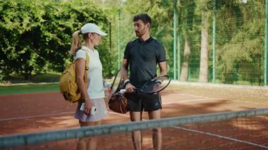 Güneş ışığında spor giyim sektöründe kadın ve erkek raketler ve spor müsabakalarıyla tenis hakkında konuşuyorlar. Genç sporcu kadın spor yavaş çekim antrenmanı yapıyorlar.