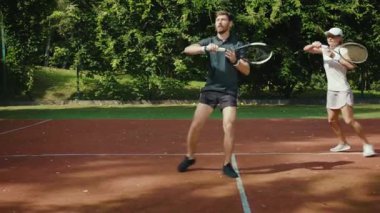 Genç bir kadın ve erkek tenis oynuyorlar. Atletik güçlü atletik oyun antrenmanı. Boş zamanlardaki spor tenis topunu yavaş çekimde oynuyorlar.