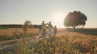 Anne ve babalarının sevgi dolu mutlu aileleri ve onların muhteşem çocukları açık havada güneşli bir günde el ele tutuşuyorlar. Güzel doğa. İlişkiler.