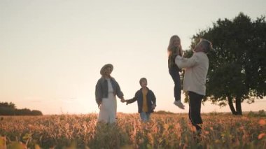 Sevimli aile anları. Kırsal kesim. Sevimli ailenin dört üyesi birlikte oynuyor, sahada koşuyor ve mutluluğu paylaşıyor.