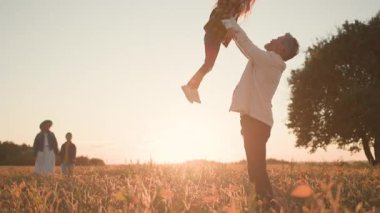 Aile birlikte vakit geçiriyor. Mutlu baba atarken, sevgili kızını yakalarken ve eğlenirken. Genç anne oğluyla güneşli arazide yürüyor..