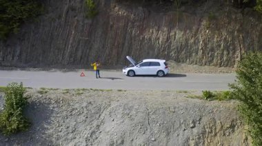 Hava aracı görüntüsü. Kırık beyaz arabalı genç Afro-Amerikalı kadın. Bozuk araba arızası..