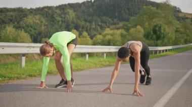 Etkin çok ırklı takım sporları yolda vücut egzersizleri yapıyor. Açık hava antrenmanından önce kadın ve sporcu yakışıklı bir adam konuşuyor..
