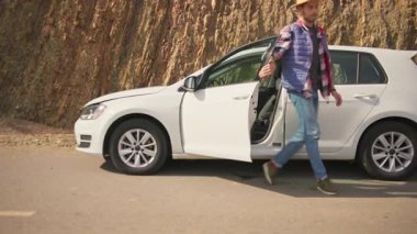 Yol kenarında duran bir adam, arabasını kontrol ediyor ve içinde hasarlı bir motor buluyor. Araba arızası. Yolda bir kaza oldu. Gezgin. Stresli bir durum..