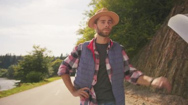 Stresli, genç, sakallı bir gezgin yol kenarında duruyor. Kaputu açık, araba arızası olan bir aracın yanında yardım bekliyor. Araba sorunu..