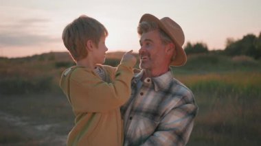 Aile portreleri. Yakışıklı, beyaz sakallı yetişkin bir adam kucağında küçük bir çocukla gülüyor ve oynuyor. Küçük çocuk babasının burnuyla oynuyor..