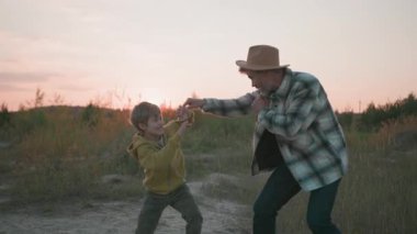 Eğlenceli bir çift yetişkin baba ve çocuk kavga ediyor, boks ve karate oynarken birlikte egzersiz yapıyorlar. Takım çalışması. Açık hava eğitimi.