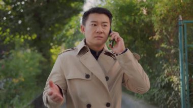 Kızgın Asyalı genç işadamı meslektaşıyla konuşuyor ve cep telefonundan olumsuz haberler aldığını iddia ediyor. İş adamı. Duygular. Stres yüzünden. Yanlış anlaşılma.