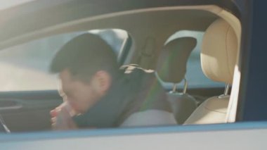 Kafkasyalı iş adamı işe giderken arabada oturuyor ve alerjisini hapşırtıyor. Grip, ateş ve boğaz ağrısı. Coronavirus belirtileri. Salgın. Sağlık Hizmetleri.