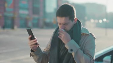 Genç, hastalıklı, atkı ve palto giyen, akıllı telefonu kullanarak internetteki eczanede hapşırma alerjisi arayan genç bir adam. Sağlık hizmetleri çalışanları.