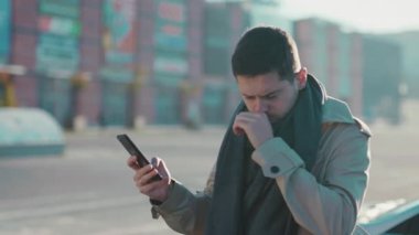 Beyaz önlüklü, hapşıran, alerjisi olan beyaz bir işadamı sokakta akıllı telefon kullanarak sağlık tedavisini arıyor. Grip oldum. Hastalık..