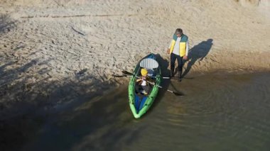 Havadan bakıldığında genç oğlu olan olgun bir baba nehirde kano sporu eğitimi alıyor. Aile sporları. Rekreasyon.