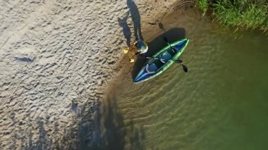 Kayak sporları eğitimi aldıktan sonra baba ve oğlunun nehir kıyısında durduğu hava manzarası. Aile eğlencesi. Yaz zamanı..