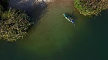 Havadan bakıldığında baba ve oğul, genç aile eğitimleri sırasında birlikte huzurlu nehirde yüzen kano kayığına binerken görülüyor. Takım aileleri. Eğlence için. Yaz.