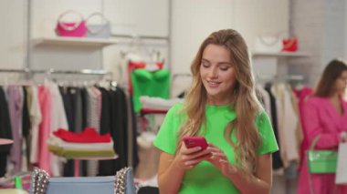 Lüks moda mağazasında çalışan çekici genç bir bayan müşterilere gülümseyen mesajlar atıyor..