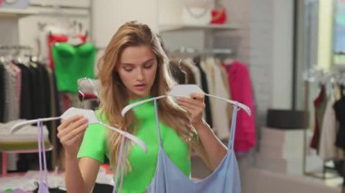 Moda genç bayan modern lüks mağazalarda iki şık giysi arasında seçim yapıyor. Alışverişkolik kız. Alışveriş hobisi.