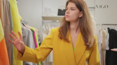 Güzel, güzel, beyaz, şık takım elbiseli bir kadın lüks mağazada yeni kıyafetler alıyor. Alışverişkolik kavram.