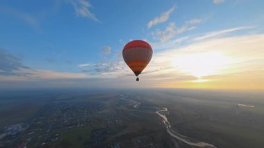 Güzel renkli sıcak hava balonunun kuşbakışı görüntüsü akşam güneşinin resimli günbatımında yüzüyor. Tatilde. Seyahat yerleri. Hava manzarası.