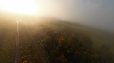 Sisli dağların üzerinden havadan FPV uçuşu, açık ilham verici doğa manzarası ve gün doğumu güneşi. Sisli bir sabah. Kuş gözü yolculuğu. İnsansız hava aracı görüntüleri.